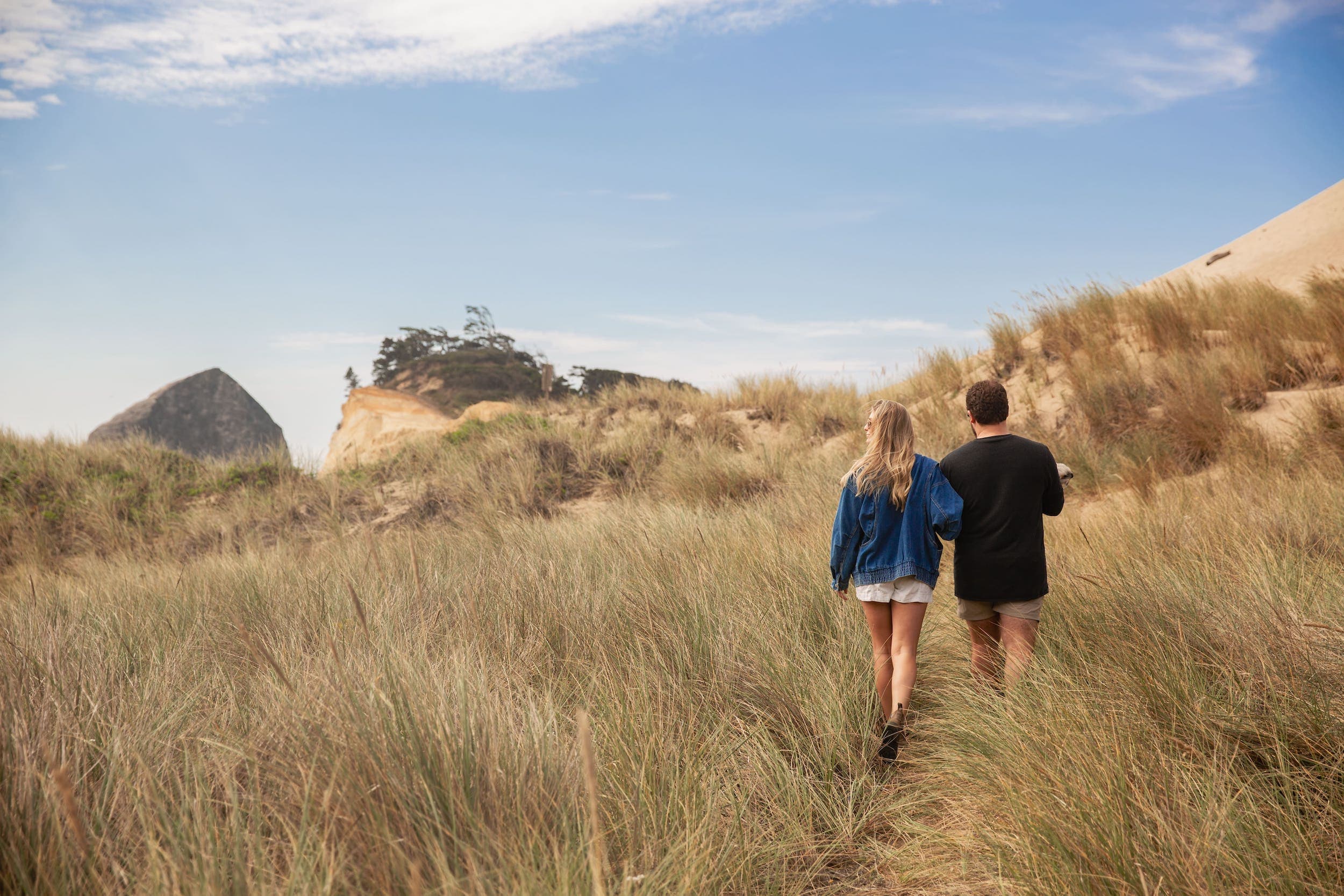 A couple walking in a sand dune near Inn at Cape Kiwanda