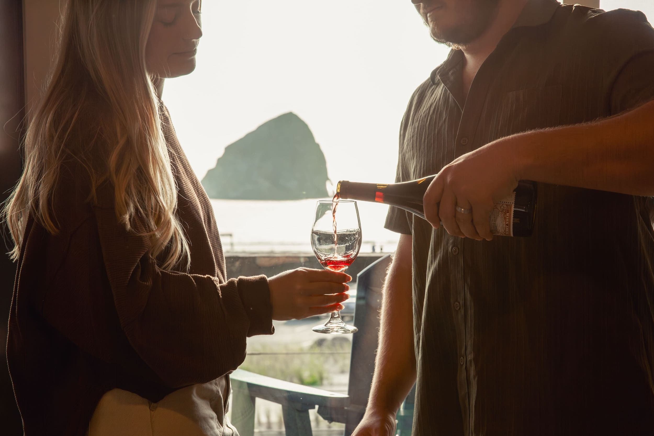 A man pouring some red win into a glass at Inn at Cape Kiwanda