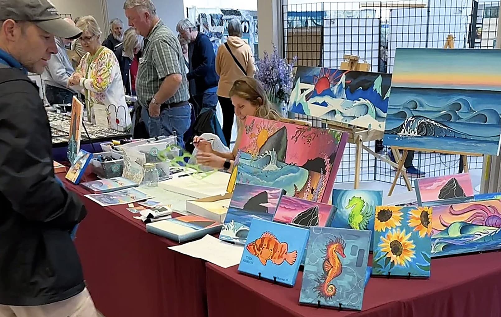 Shoppers browse coastal paintings of pelicans and Haystack Rock at Nestucca Valley Artisans art festival, Inn at Cape Kiwanda, Pacific City, Oregon Coast