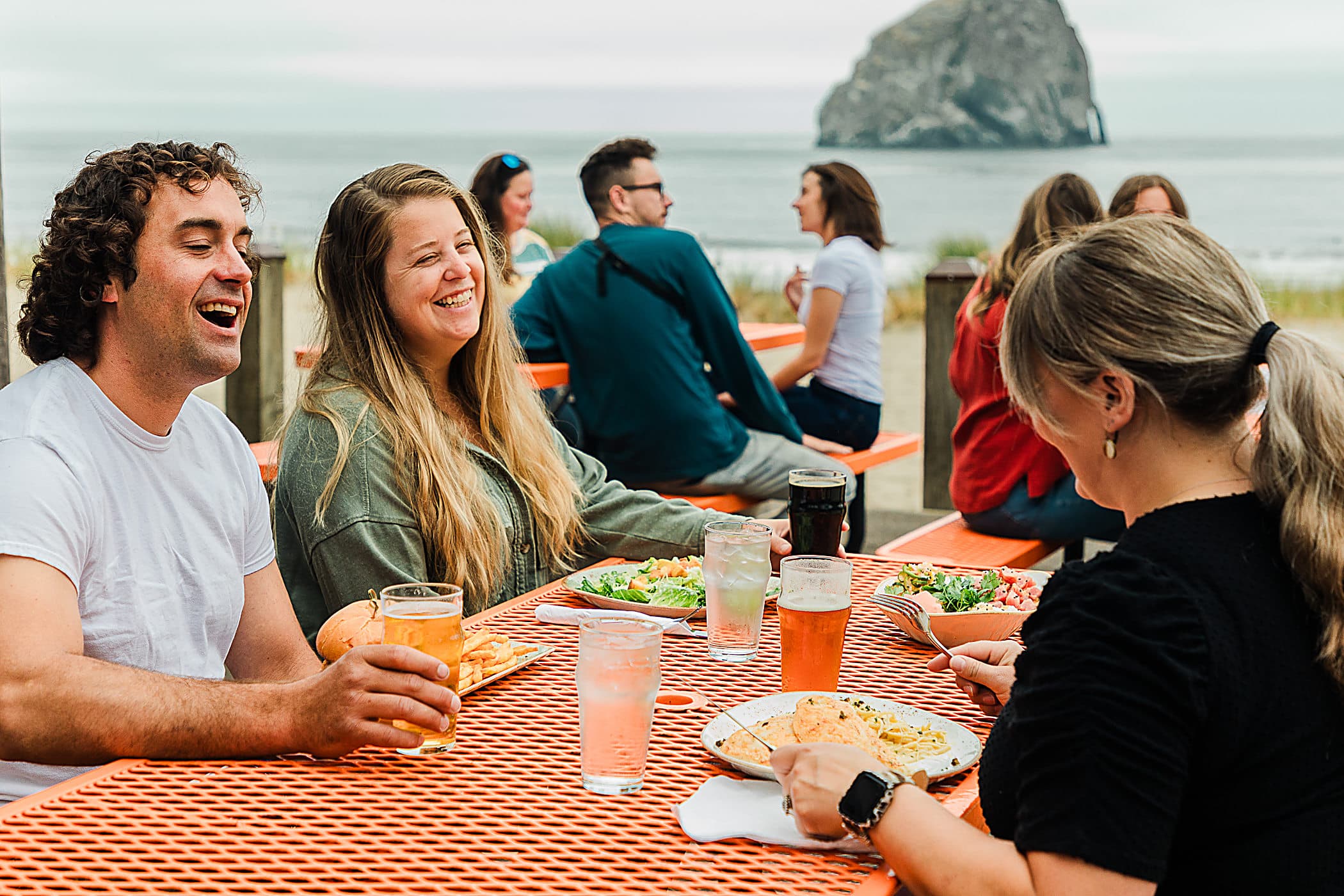 Guests dining outdoors with beer and ocean views near Haystack Rock, Pacific City, Oregon Coast
