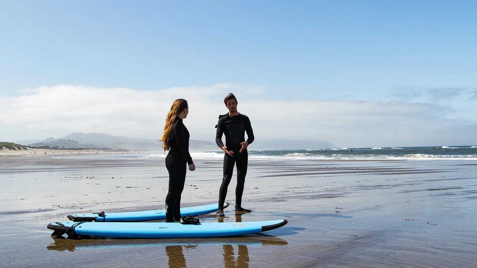 Surf instructor coaching a student on the beach at Cape Kiwanda, Pacific City, Oregon Coast