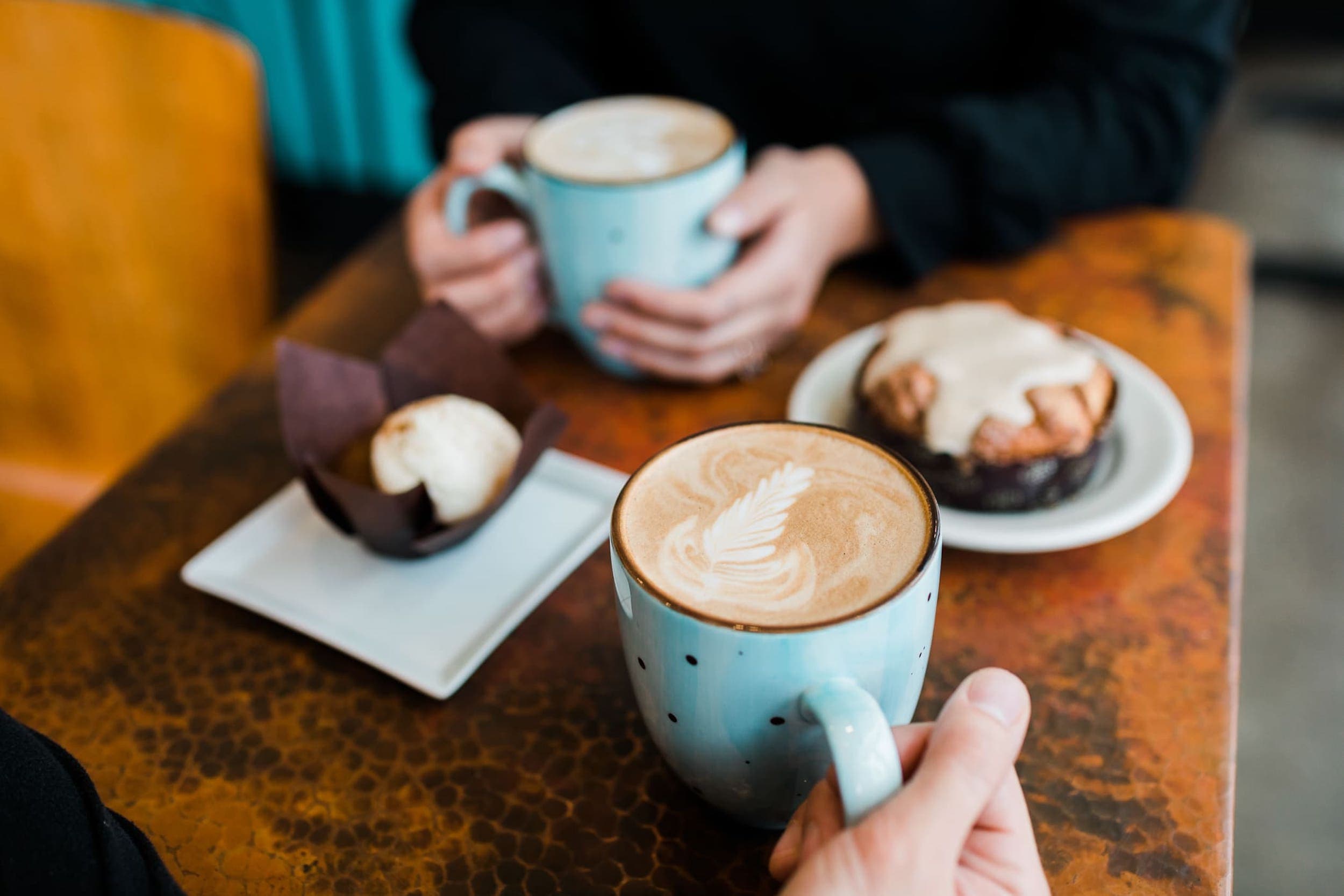 Two people sitting inside Stimulus Coffee having warm drinks and snacks