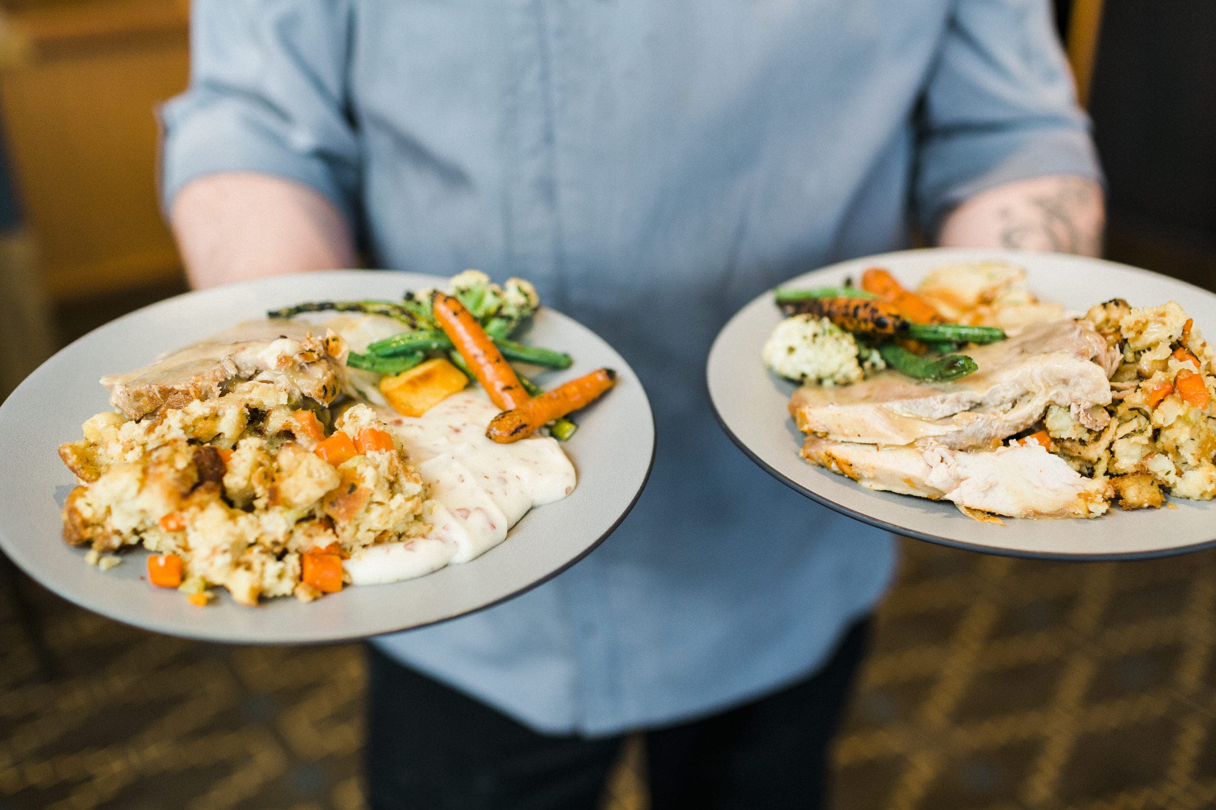 A man holding two plats of Thanksgiving dinner at Headlands Meridian restaurant