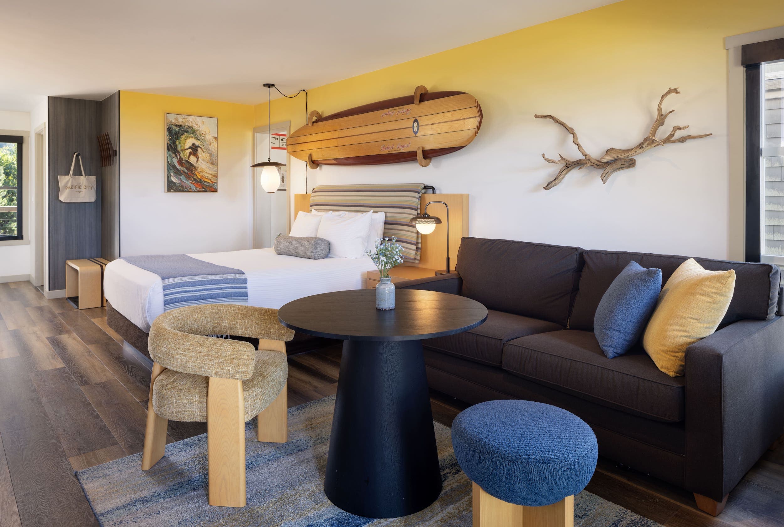 Inn At Cape Kiwanda ONeill Suite With Bunk room with vintage surfboard on the wall above a queen bed, and an open concept living space