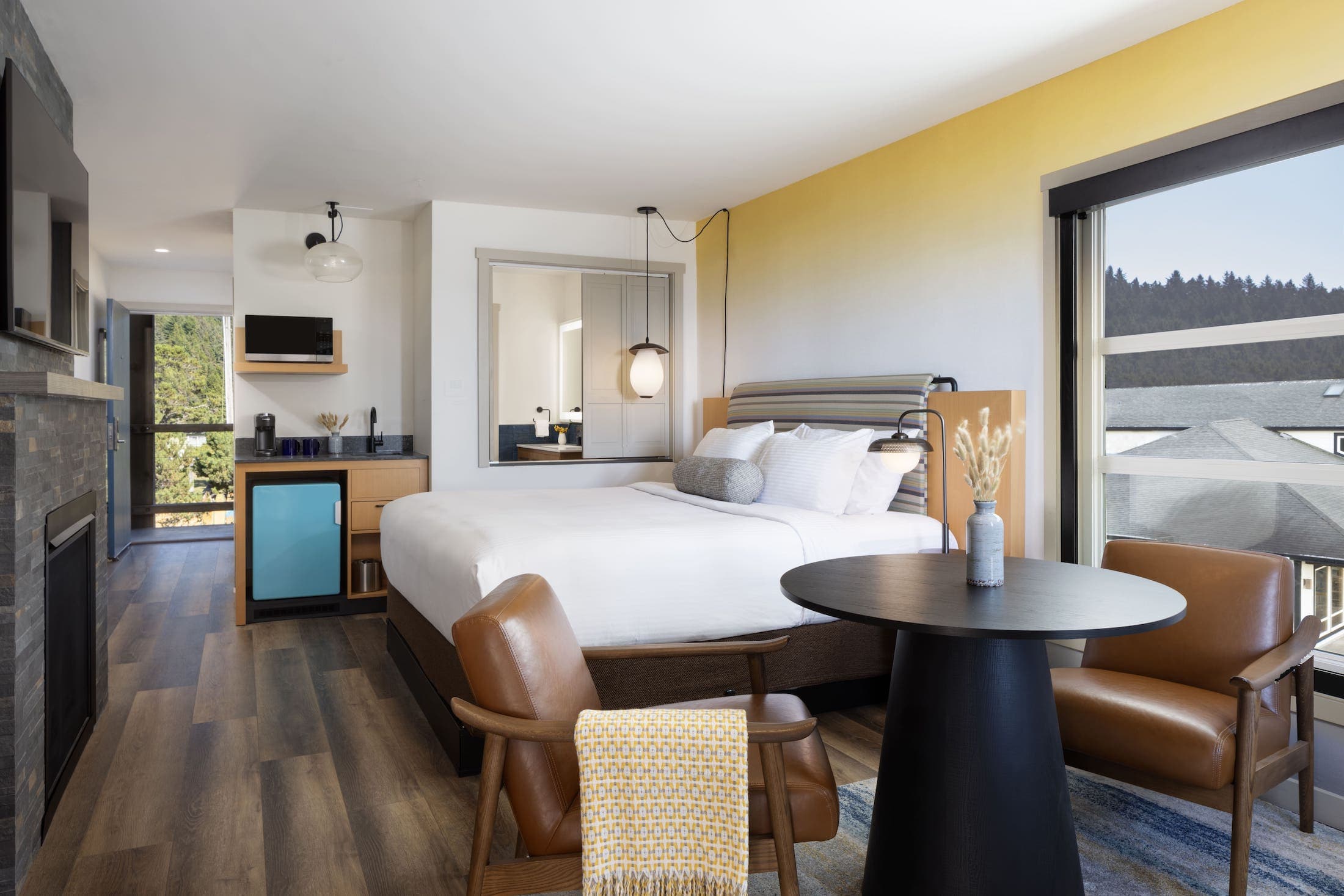 Inn At Cape Kiwanda Top Floor King Jetted Tub room with a fireplace, large TV, table with two chairs, and kitchenette