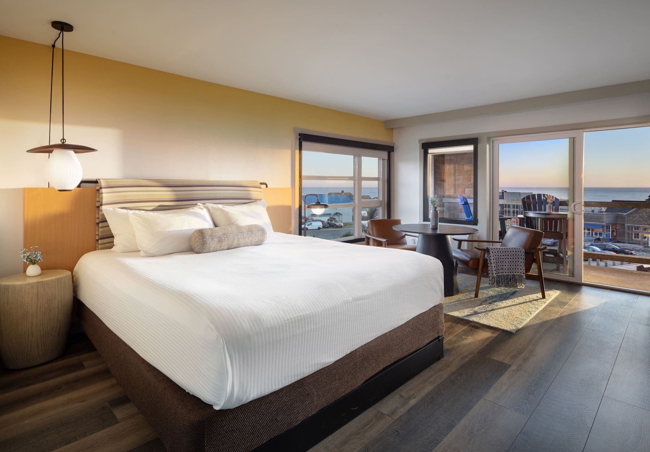 Inn At Cape Kiwanda Top Floor King Jetted Tub room with a king bed, table with two chairs, and a balcony with a view of the ocean