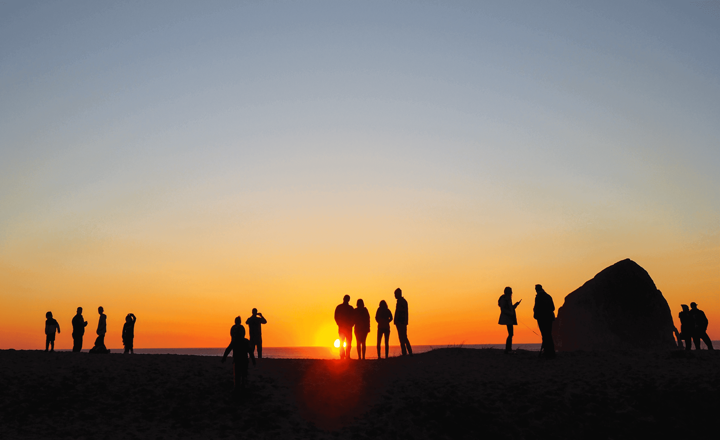 A group of people at the beach during sunset