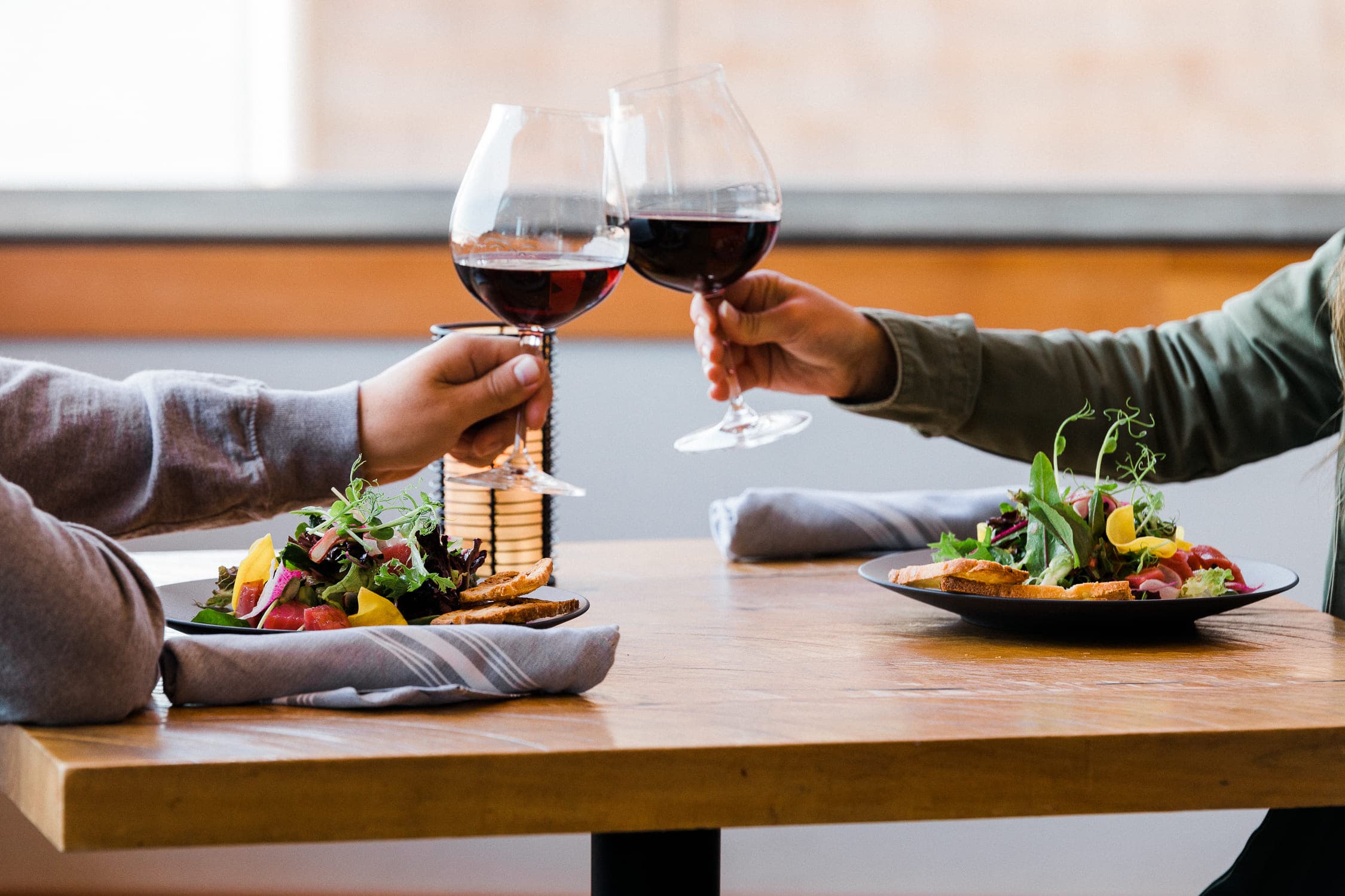 A couple eating dinner and cheers-ing glass of red wine at Coastal Chords & Corks event