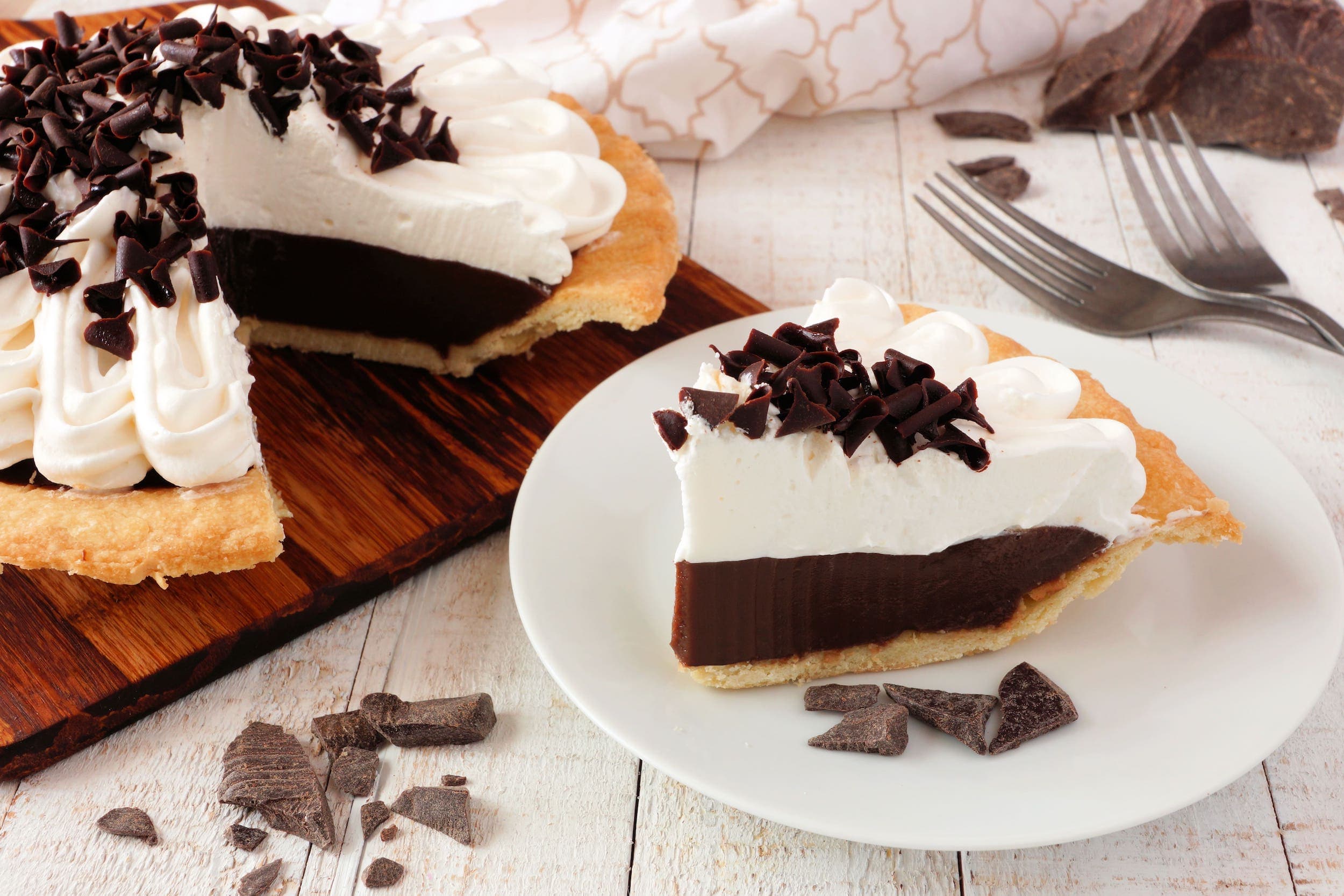 A chocolate cream pie on a plate on a wooden table