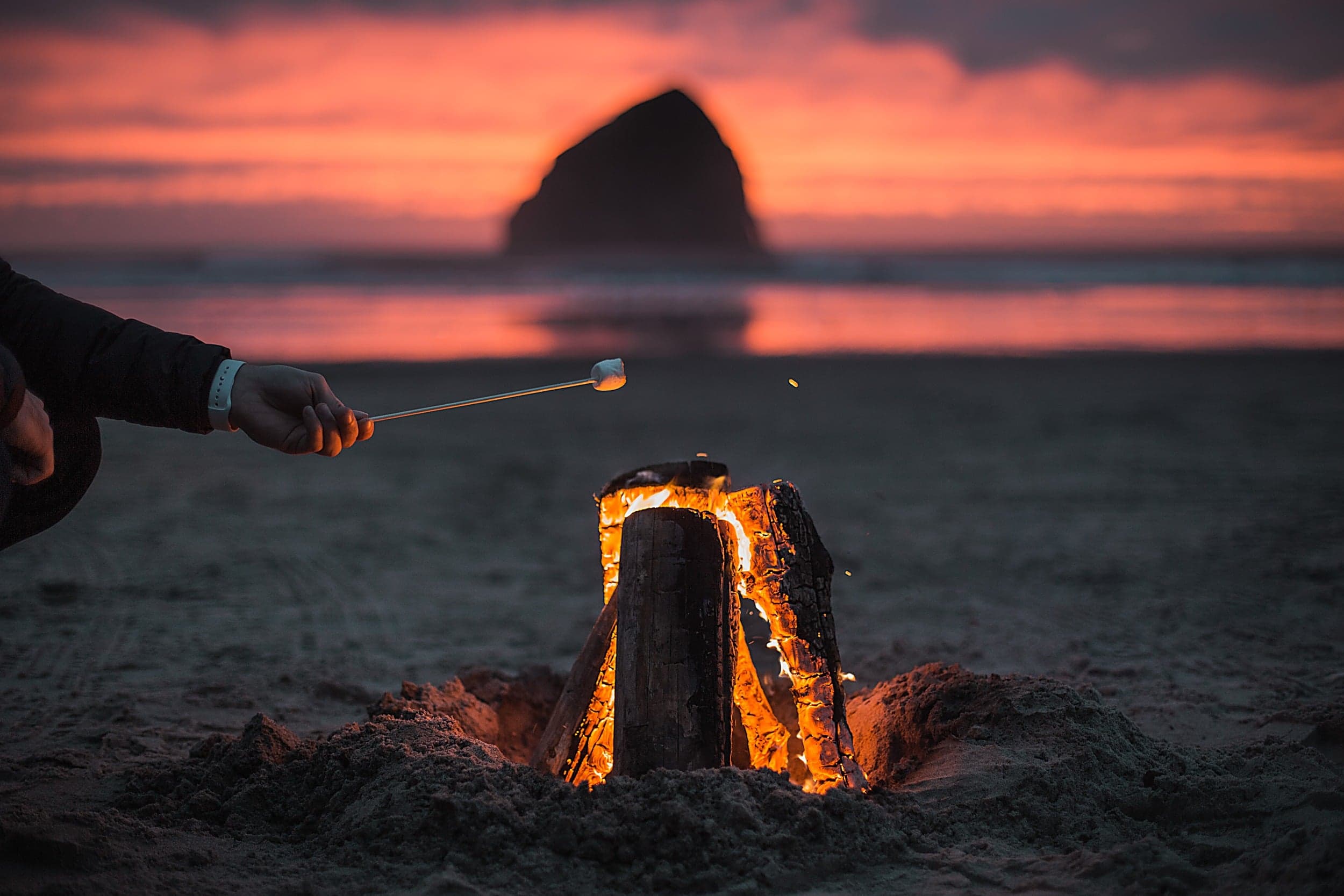 Roasting a marshmallow over a beach bonfire near Haystack Rock, Inn at Cape Kiwanda, Pacific City, Oregon