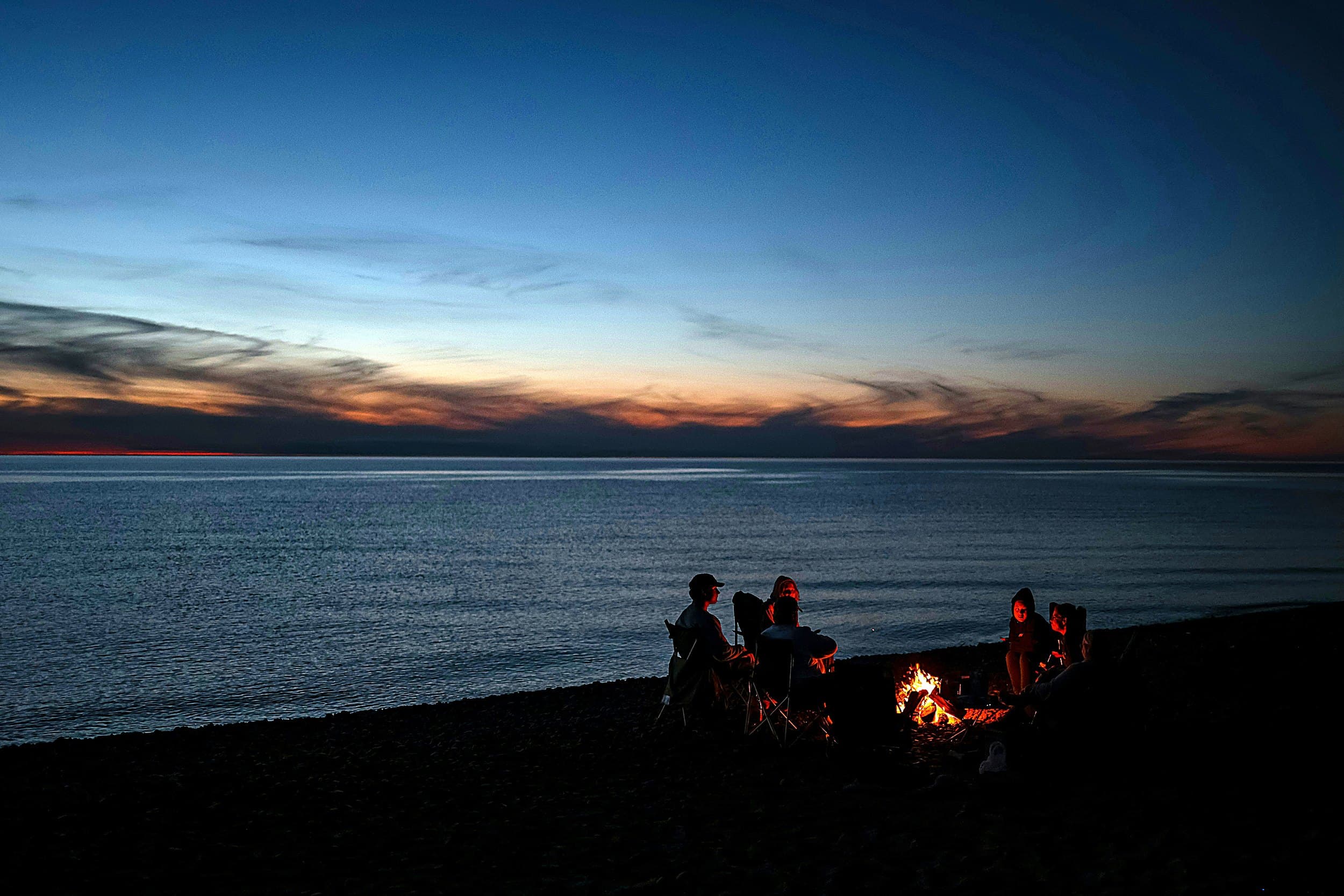 Friends gathered around a beach bonfire at sunset near the Inn at Cape Kiwanda, Pacific City, Oregon Coast