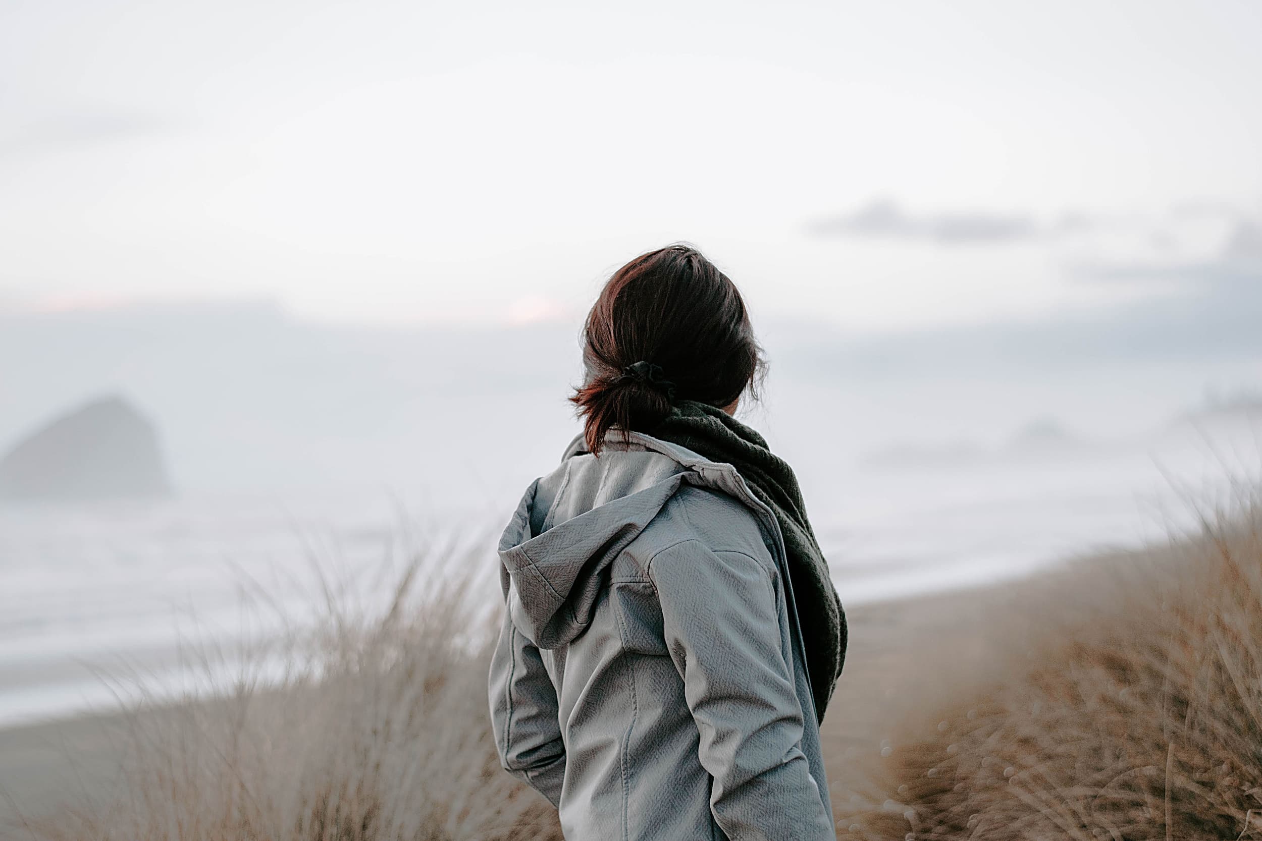 Woman watching winter surf from the dunes near the Inn at Cape Kiwanda, Pacific City, Oregon Coast