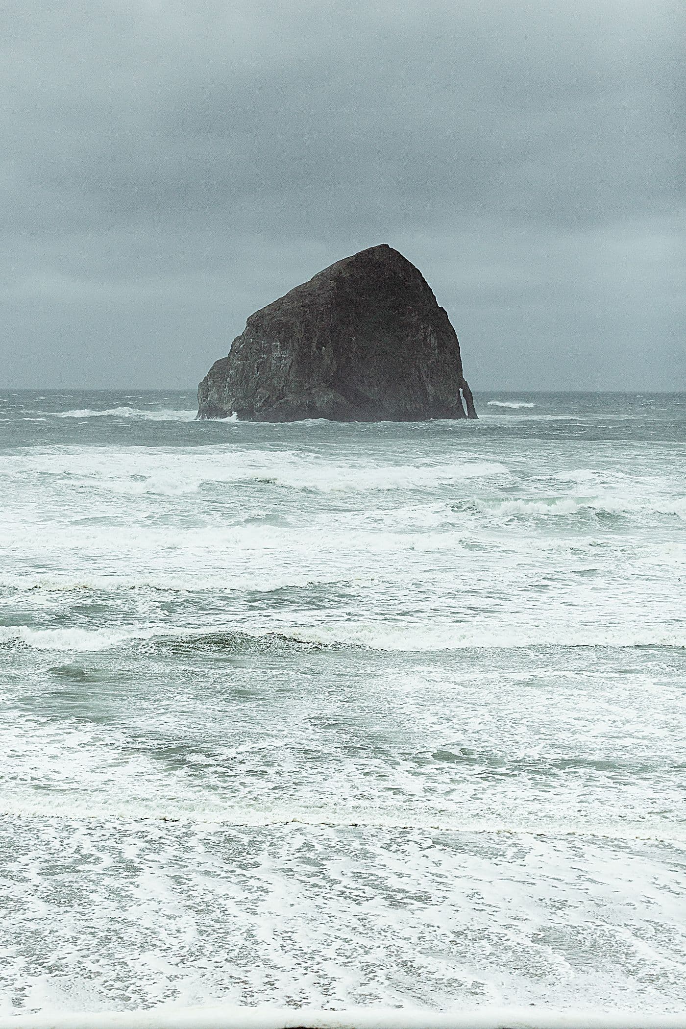 Haystack Rock rising from stormy king tide surf offshore from the Inn at Cape Kiwanda, Pacific City, Oregon Coast