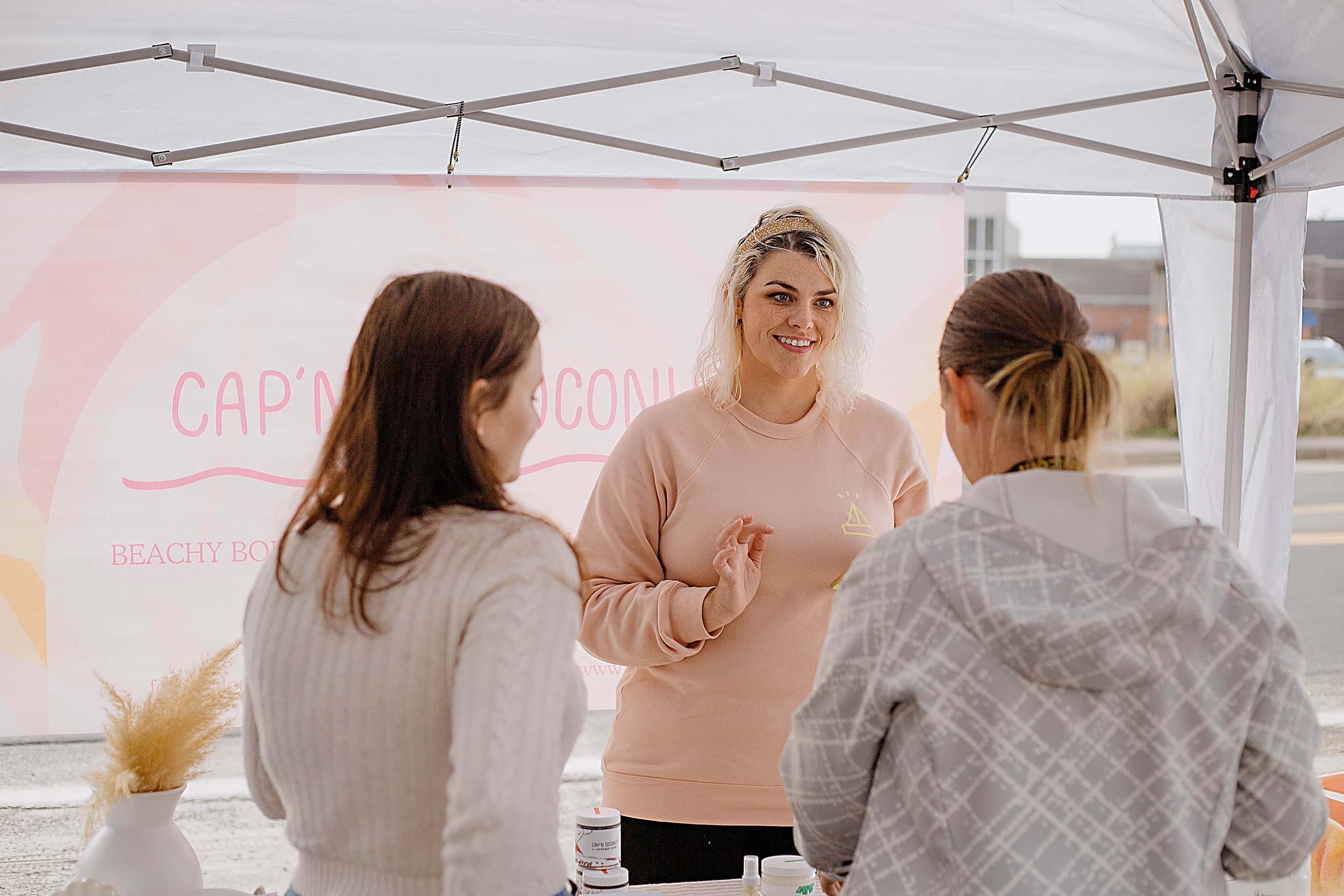 Local maker sharing handmade beach-inspired body care at the Fall Festival artisan market, Pacific City, Oregon Coast