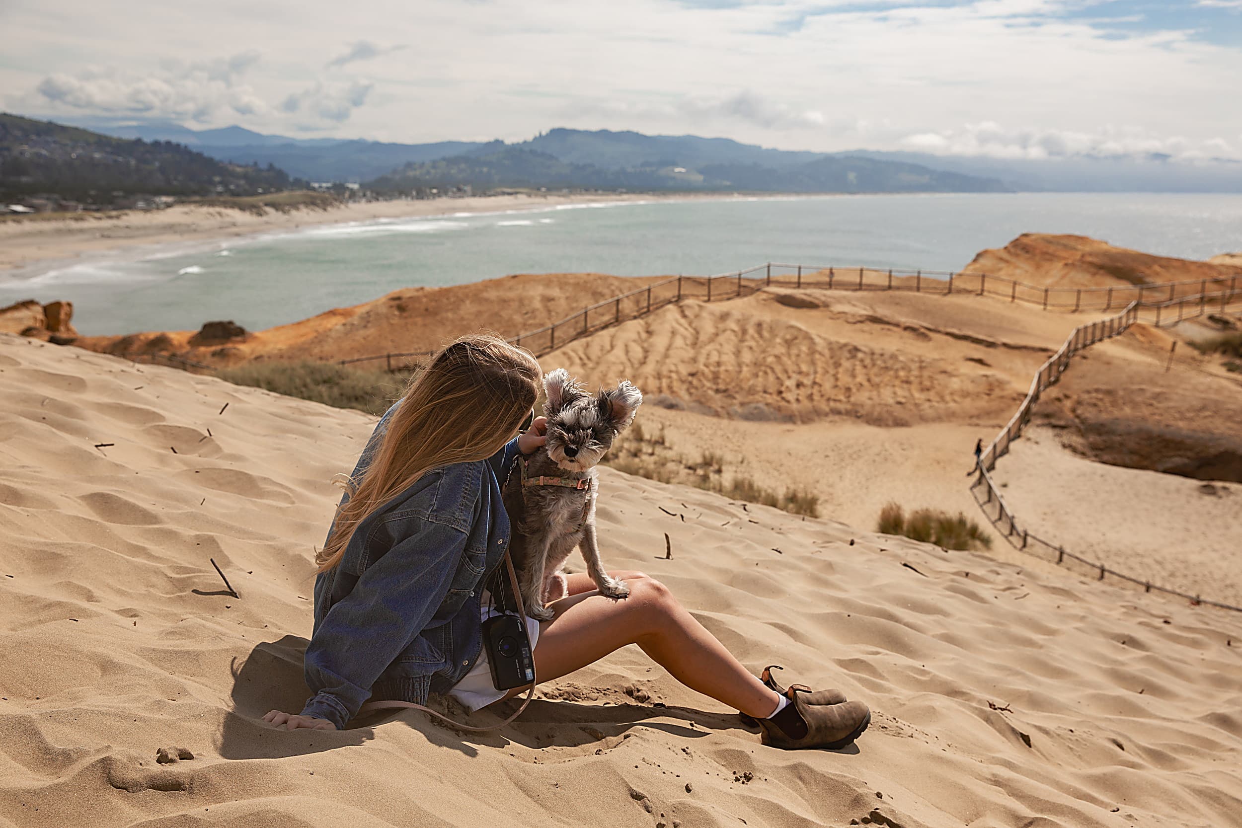 Woman and her dog on the Cape Kiwanda sand dune overlooking Pacific City beach, Inn at Cape Kiwanda, Oregon Coast.