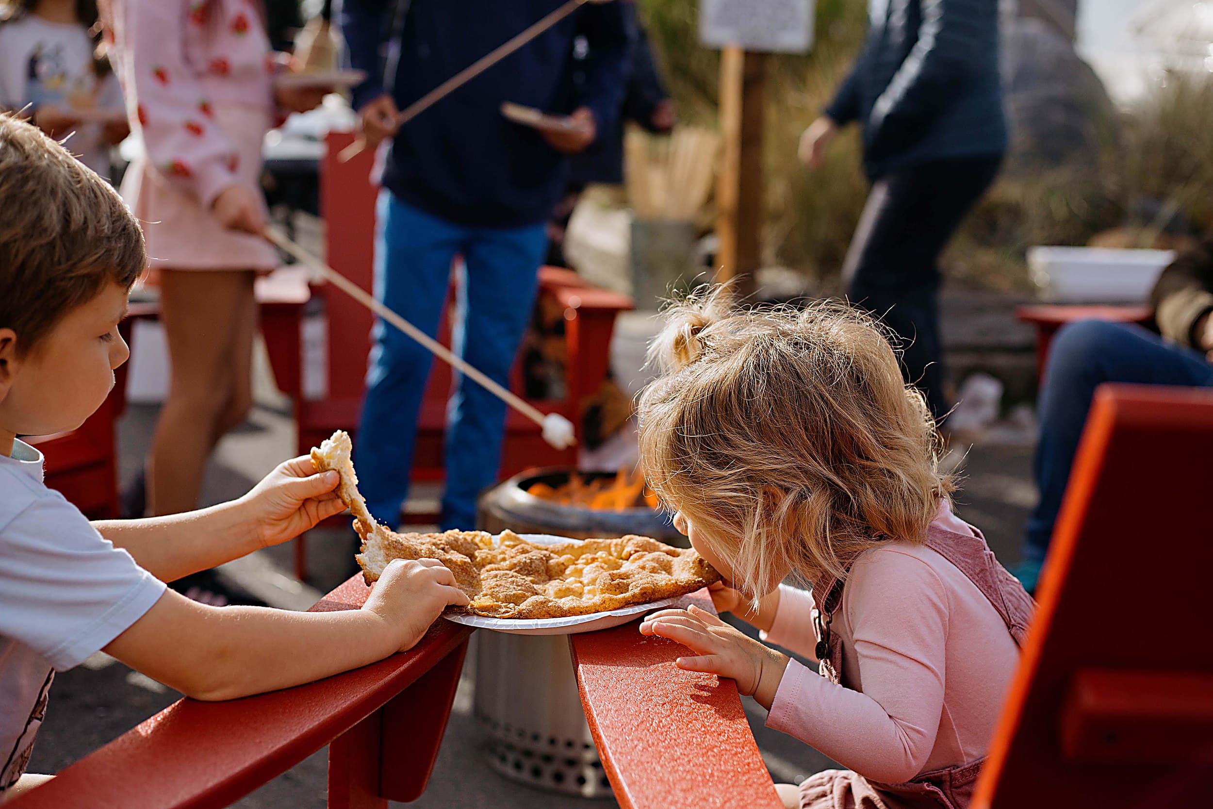 Children sharing a funnel cake beside a fire pit at the Fall Festival, Cape Kiwanda, Pacific City, Oregon Coast